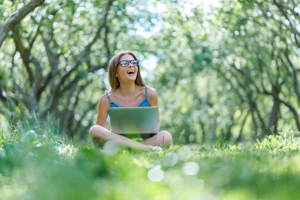 Student with notebook in park looking at notebook computer