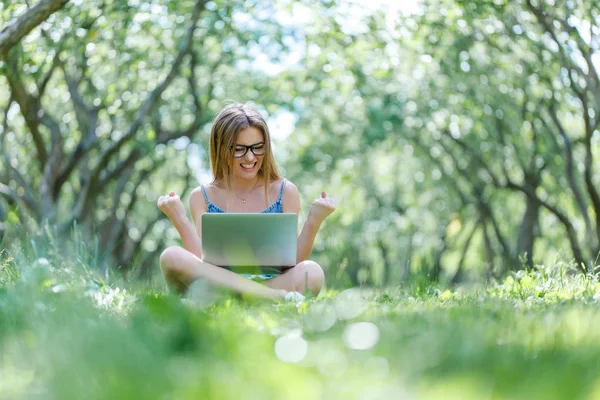 Student with notebook in park looking at notebook computer