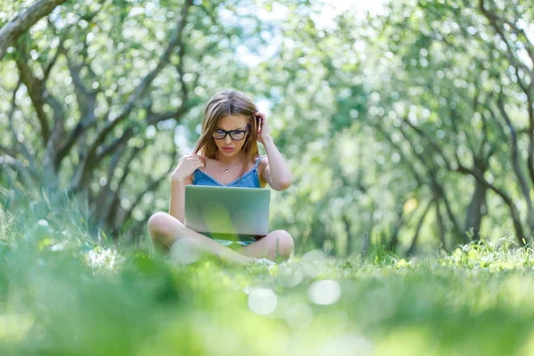 Student with notebook in park looking at notebook computer