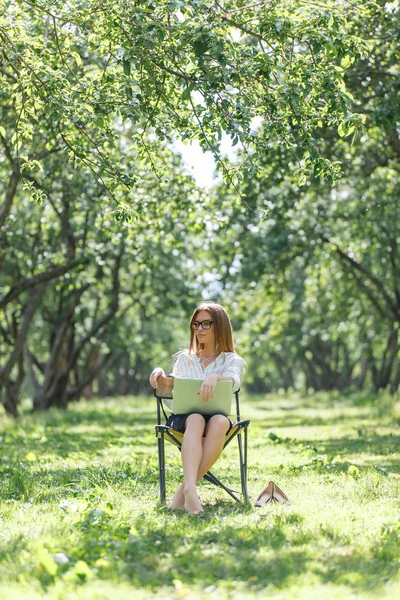 Girl with laptop in the park sitting on a folding chair