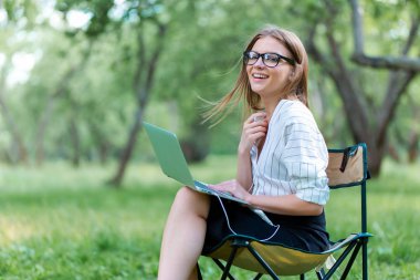 Kadın parkta katlanır iskemlede bir dizüstü bilgisayar ile