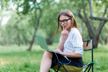 Kadın parkta katlanır iskemlede bir dizüstü bilgisayar ile
