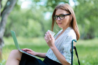 Öğle Yemeği dizüstü bilgisayar kullanan kız şehir parkında break ve kahve onun elinde tutmak