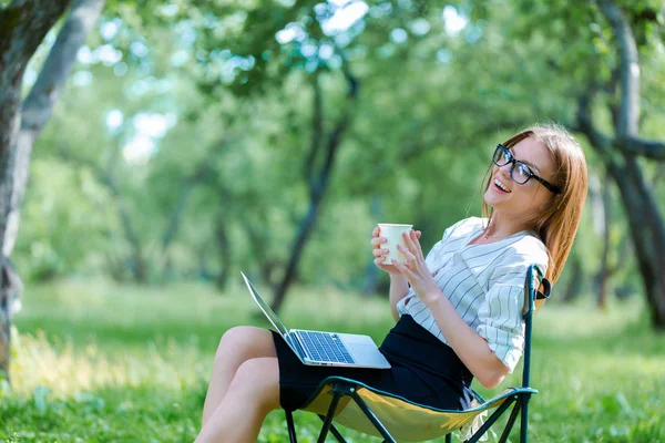 Öğle Yemeği dizüstü bilgisayar kullanan kız şehir parkında break ve kahve onun elinde tutmak