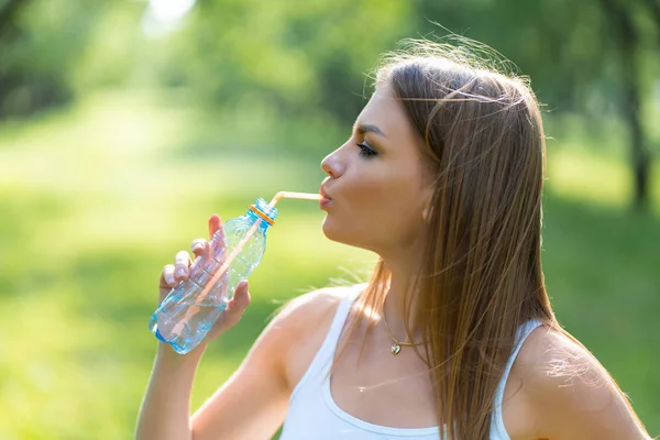 健身年轻美丽的女孩在公园锻炼后喝水 — 图库照片
