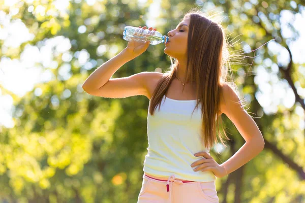 健身年轻美丽的女孩在公园锻炼后喝水 — 图库照片