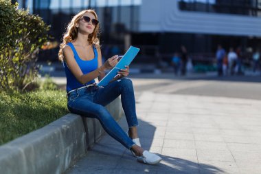 Sokakta elinde bir defter tutan genç ve güzel bir kadın. İş ya da eğitim yaşam tarzı kavramı