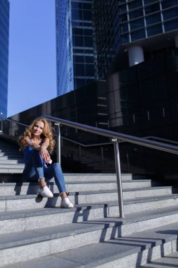 Onun smartphone ile gökdelenler arasında adımları üzerinde oturan güzel kadın