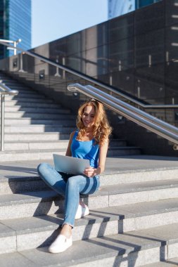 Onun bilgisayar ile gökdelenler arasında adımları üzerinde oturan güzel kadın