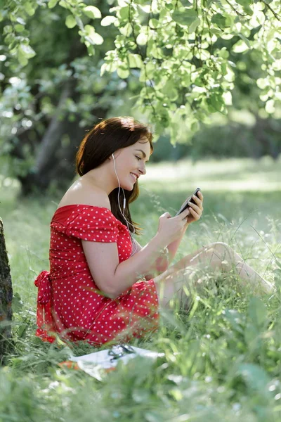 Jovem Mulher Bonita Sentada Grama Sob Árvore Usando Seu Smartphone — Fotografia de Stock