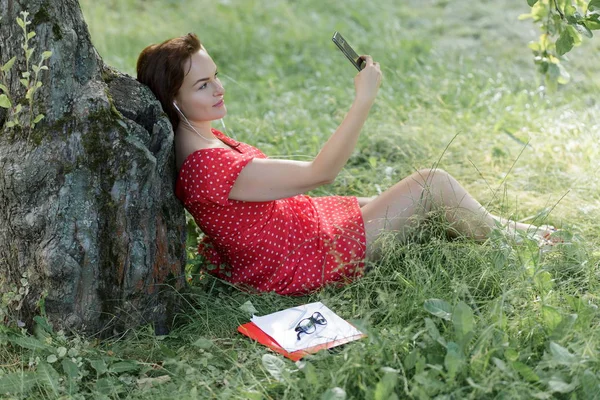 Giovane Donna Seduta Sull Erba Sotto Albero Con Suo Smartphone — Foto Stock
