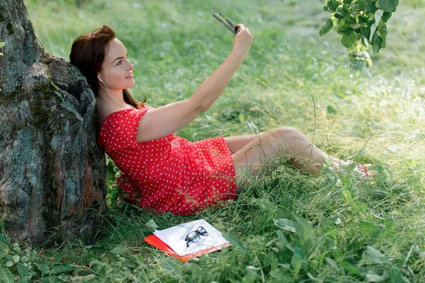 Jovem Mulher Sentada Grama Sob Árvore Com Seu Smartphone Leva — Fotografia de Stock