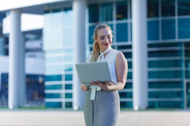 Bir iş merkezinin ortasında bir dizüstü bilgisayar kullanarak başarılı iş kadını