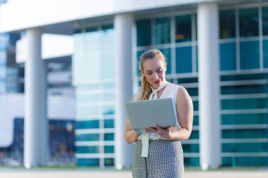 Bir iş merkezinin ortasında bir dizüstü bilgisayar kullanarak başarılı iş kadını