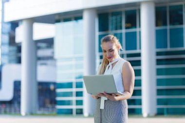 Bir iş merkezinin ortasında bir dizüstü bilgisayar kullanarak başarılı iş kadını