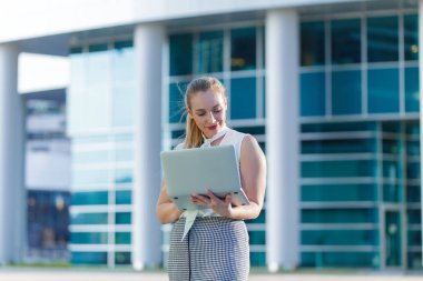 Bir iş merkezinin ortasında bir dizüstü bilgisayar kullanarak başarılı iş kadını