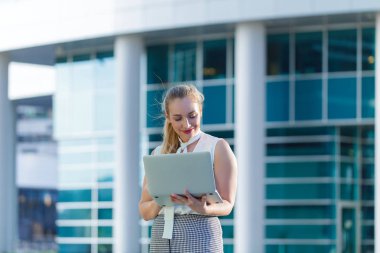 Bir iş merkezinin ortasında bir dizüstü bilgisayar kullanarak başarılı iş kadını