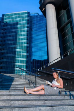 Bir iş merkezinin ortasında kitap okuma başarılı iş kadını