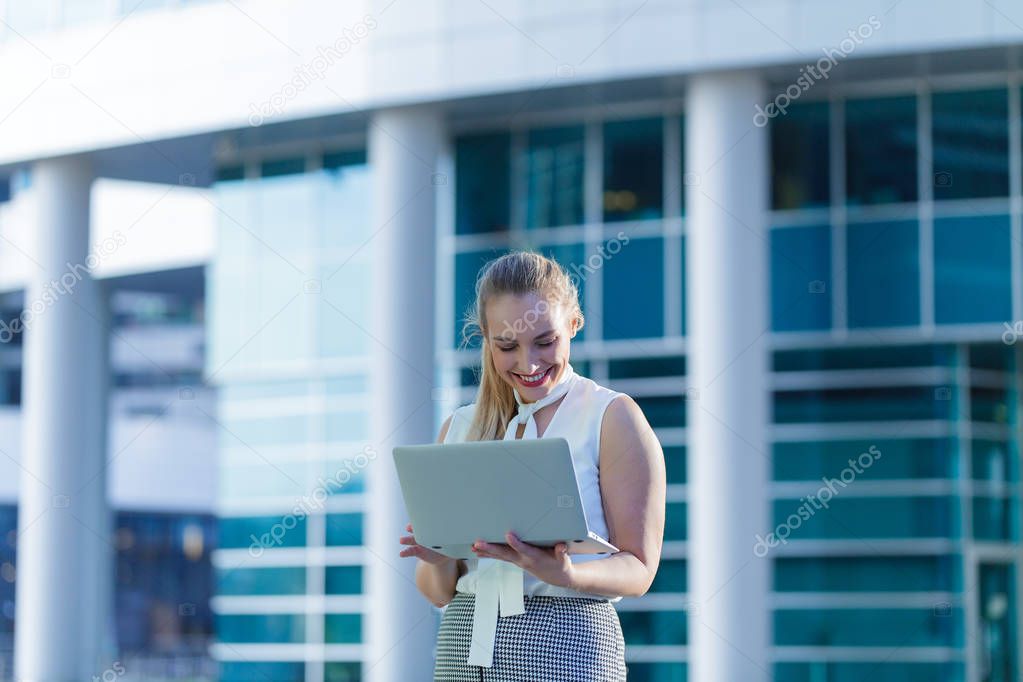 Successful business lady using a laptop in the middle of a business center