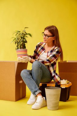 Kutusu arasında bir araç kutusu üzerinde oturan bir çiçek tutan genç kadın