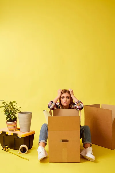 Una donna seduta nel bel mezzo di scatole mobili. Persone che si muovono nuovo p — Foto Stock
