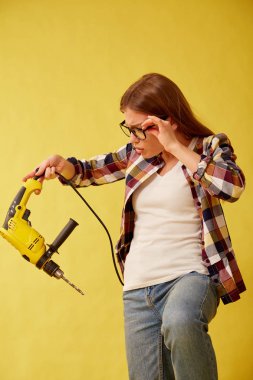 Kutuları arasında duran bir matkap tutan kız korkmuş. Stüdyo