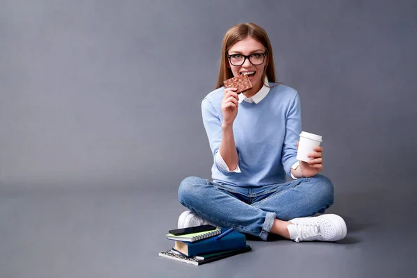 Студент ест шоколад и пьет кофе. Концепция студента. Студия — стоковое фото