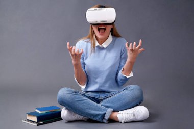 Gri bir arka plan üzerinde duran Vr gözlüklü okuma öğrenci.