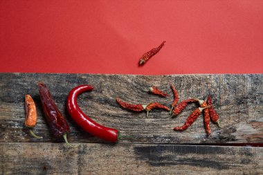 Kurutulmuş biber kırmızı bir arka plan görüntüsü üzerinde ahşap kurullarında yalan. Yakın çekim.