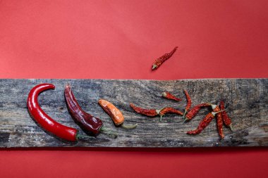 Kurutulmuş biber kırmızı bir arka plan görüntüsü üzerinde ahşap kurullarında yalan. Yakın çekim.