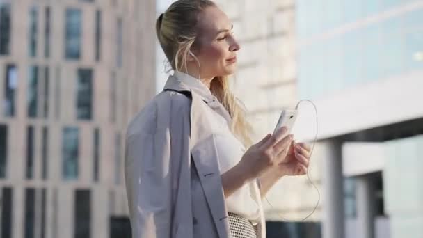 Young successful business woman listening to music using a laptop in the middle of a business center — Stock Video