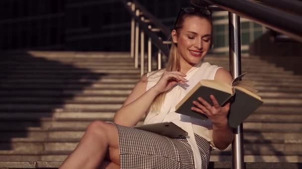 Porträt einer erfolgreichen jungen Geschäftsfrau, die inmitten eines Business Centers ein Buch liest — Stockvideo