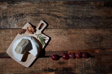 Üzüm ile ahşap masada biberiye ile gemide taze Camembert peynir. Üst görünüm