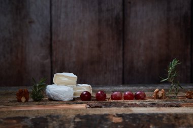 Ahşap masada üzüm ve biberiye ile yumuşak gurme peynir