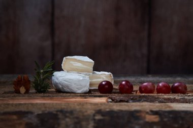 Ahşap masada üzüm ve biberiye ile yumuşak gurme peynir