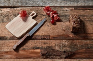 Ahşap plakalar üzerinde Prosciutto ve sakaegrain ekmek dilimleri ile düzenlenmiş korkvida üst görünümü