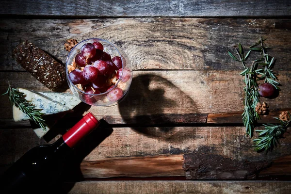 Стекло, наполненное спелым виноградом на столе с ароматным голубым сыром и хлебом с бутылкой вина — стоковое фото
