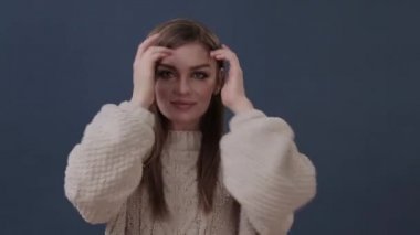 Saçlarını tarayan, kameraya bakıp gülümseyen güzel bir genç kadının portresi.