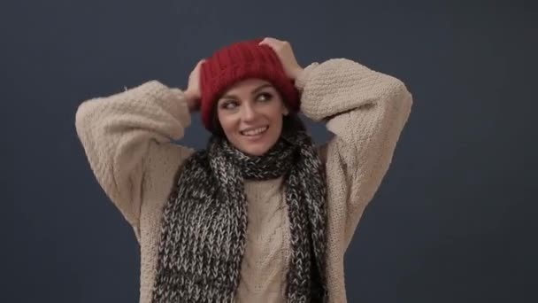 Vacker ung kvinna i halsduk sätter på hatt och ler — Stockvideo