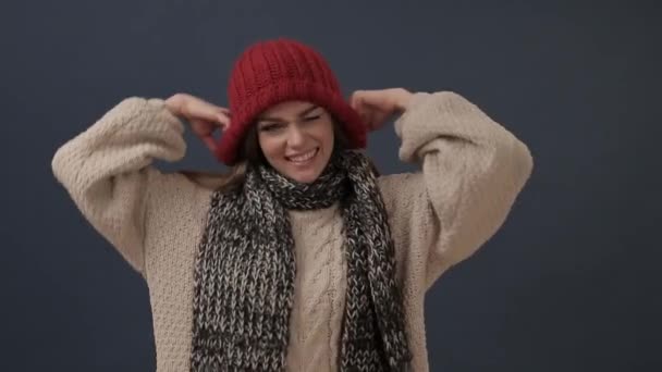 Hermosa joven en bufanda se pone el sombrero y sonríe — Vídeos de Stock