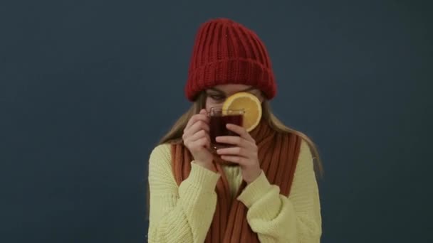Krásná mladá žena v šálu a v klobouku pije horký čaj nebo svačkový víno s oranžovým — Stock video