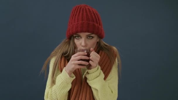 Hermosa joven en bufanda y sombrero bebiendo té caliente o vino caliente con naranja — Vídeos de Stock