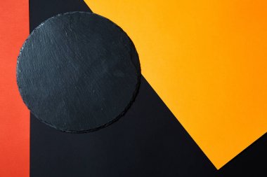 Geometrik kompozisyon ile çok renkli arka plan üzerinde boş siyah kayrak servis tahtası yukarıdan
