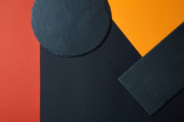 Geometrik kompozisyon ile çok renkli arka plan üzerinde boş siyah kayrak servis tahtası yukarıdan