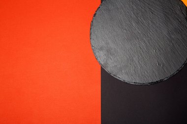 Geometrik kompozisyon ile çok renkli arka plan üzerinde boş siyah kayrak servis tahtası yukarıdan