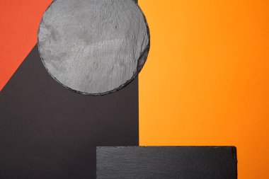 Geometrik kompozisyon ile çok renkli arka plan üzerinde boş siyah kayrak servis tahtası yukarıdan