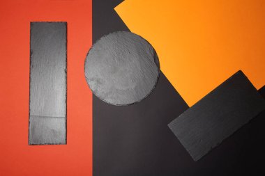 Geometrik kompozisyon ile çok renkli arka plan üzerinde boş siyah kayrak servis tahtası yukarıdan