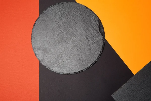 Geometrik kompozisyon ile çok renkli arka plan üzerinde boş siyah kayrak servis tahtası yukarıdan