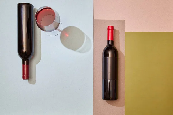 在彩色纸面上布置酒瓶和一杯红酒 — 图库照片