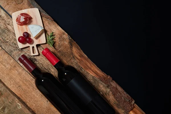 Вид сверху на подаваемые закуски на борту с бутылкой красного вина на дереве — стоковое фото